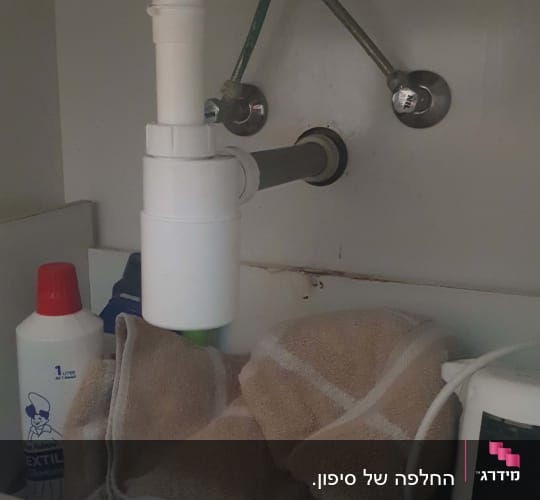 צנרת מתחת לכיור עם מגבת וחומר ניקוי
